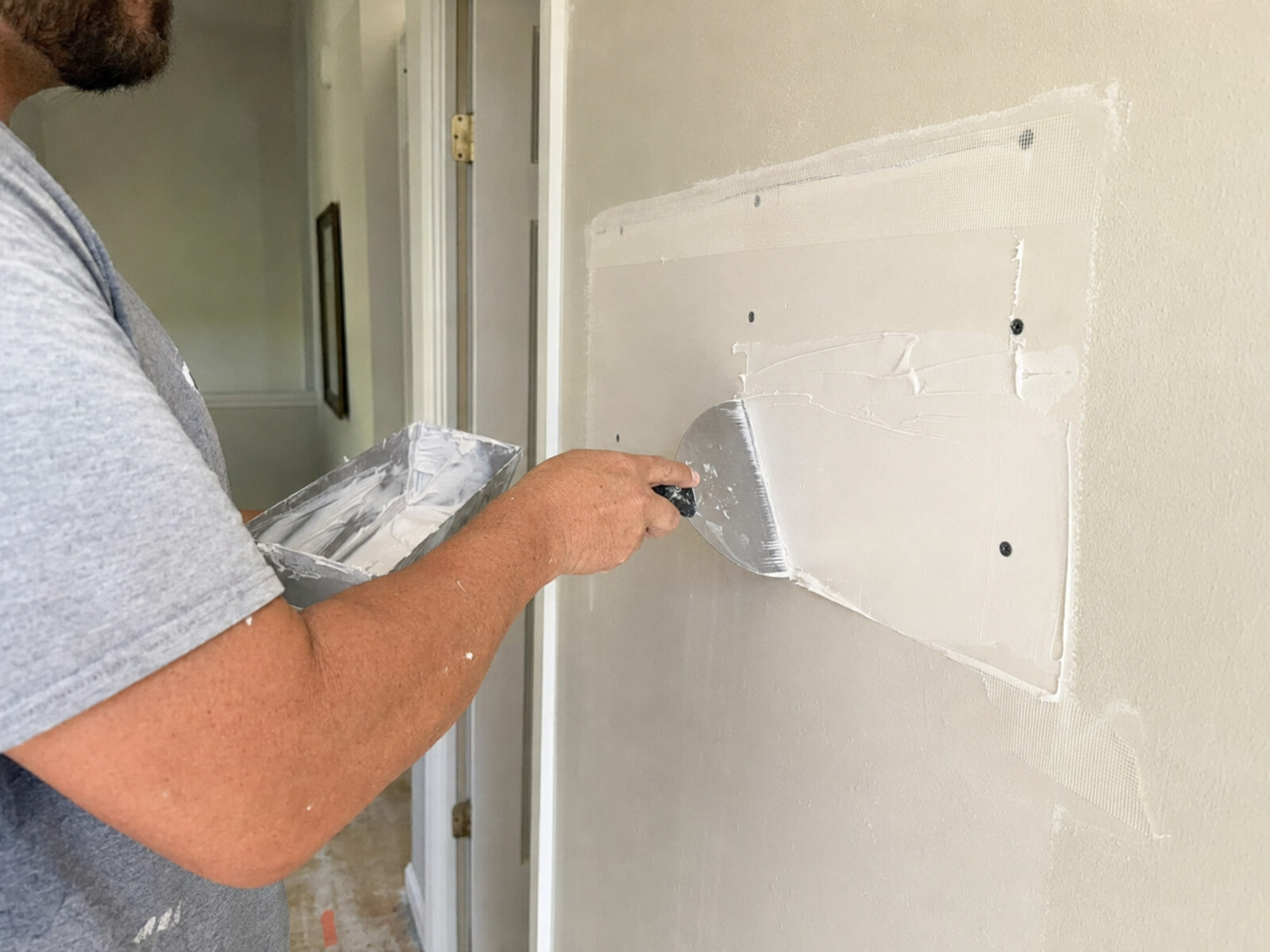 Drywall patch being installed on an interior wall