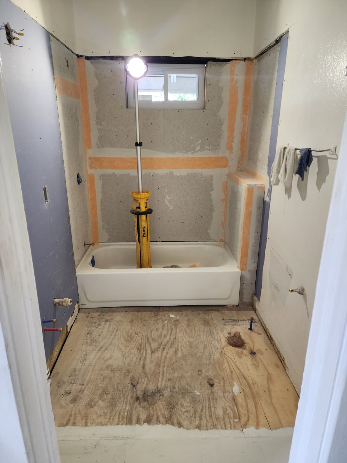 Bathroom prepared for remodeling with bathtub, cement board walls, and exposed subfloor.