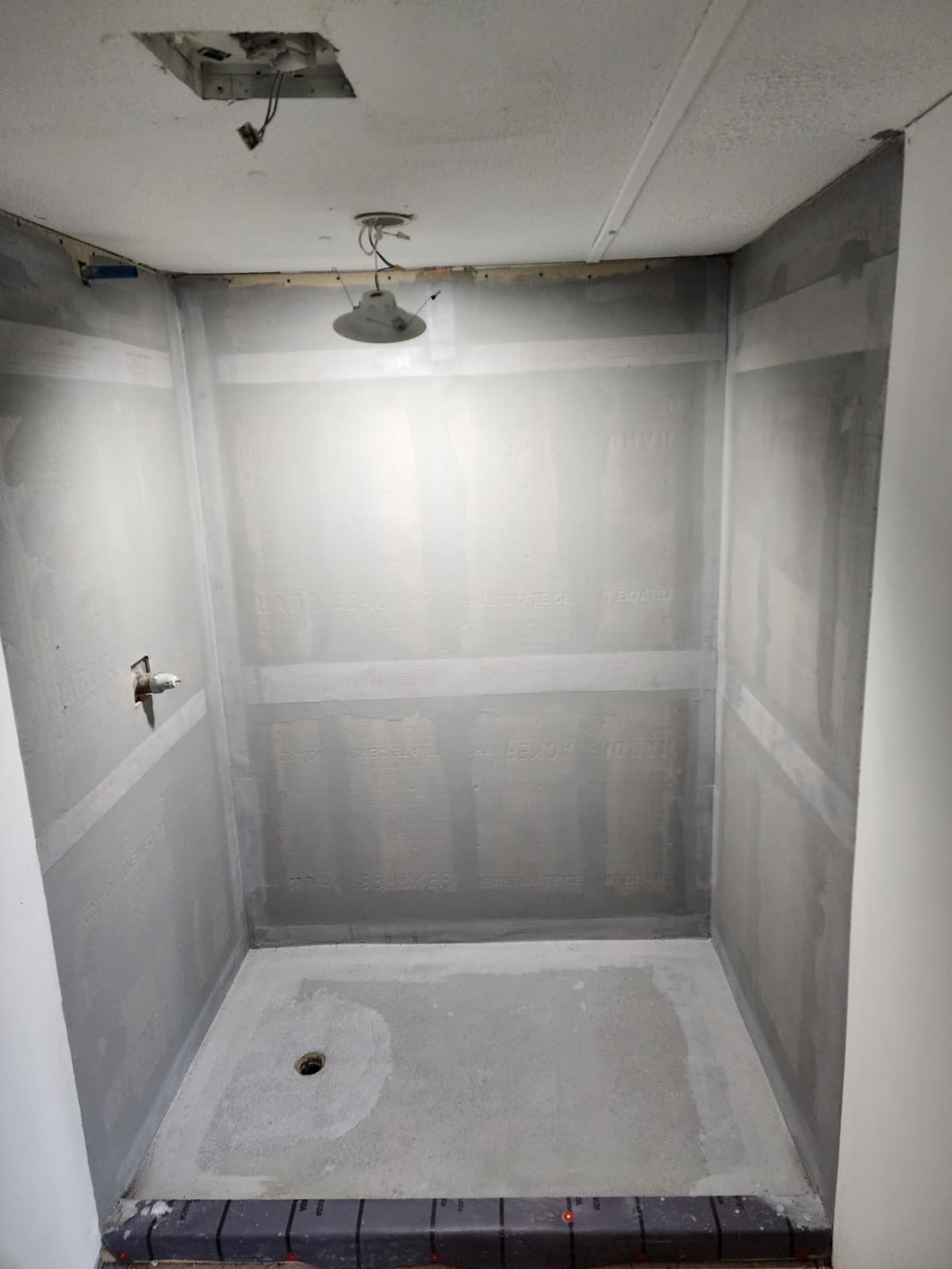 Shower stall with cement board walls and a prepared shower pan.